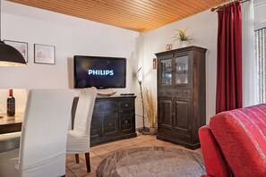 A living room with a television, a cabinet, a chair, and a sofa. - Holiday Home Godewind with Terrace, Garden, Wi-Fi & Balcony Near Beach in Otterndorf (Otterndorf)
