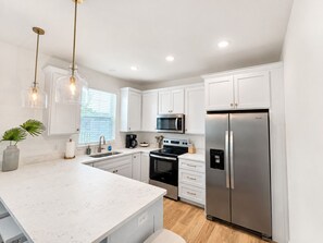 A modern kitchen with white cabinetry, stainless steel appliances, and pendant lighting. - Private Pool + New 4 Bedroom/4.5 Bath Home + Short Walk to the Beach (Panama City Beach)