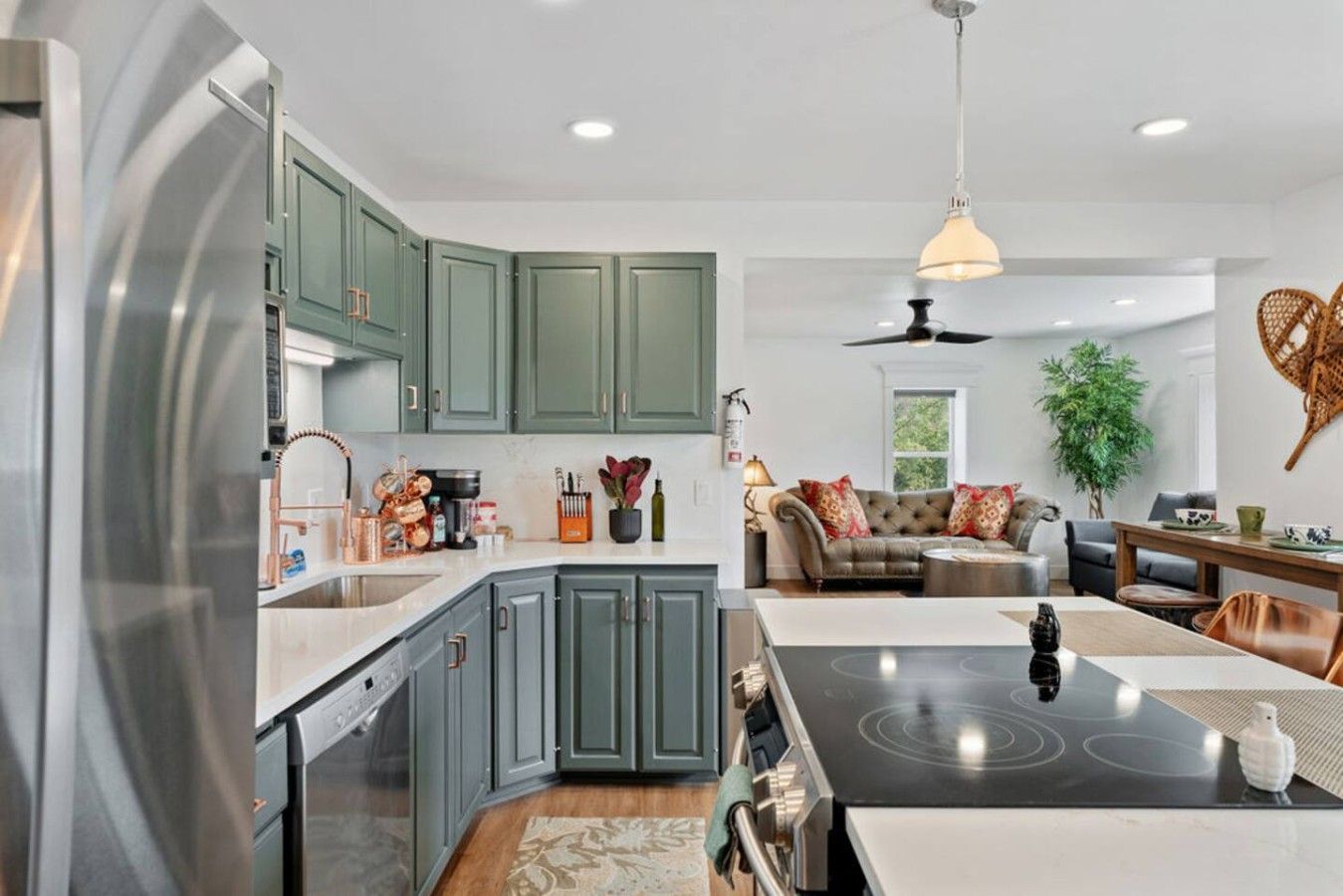 A modern kitchen with grey cabinets, a built-in oven, and a central island with a stovetop.