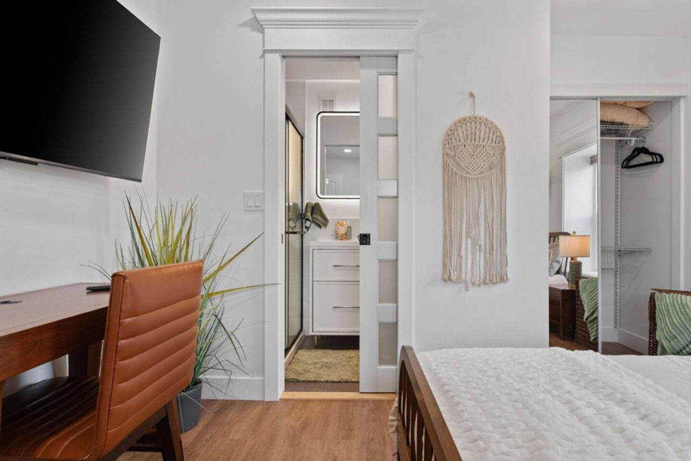 A hotel room with a bed, a desk, a chair, a TV, a wardrobe, and a mirror.