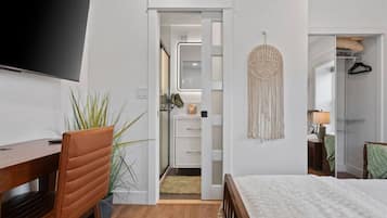 A hotel room with a bed, a desk, a chair, a TV, a wardrobe, and a mirror.