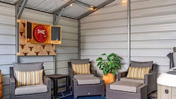 A covered outdoor seating area with wicker furniture and a potted plant.