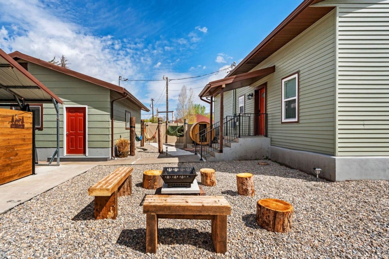 A courtyard with a wooden bench, a fire pit, and a rustic outdoor seating area.