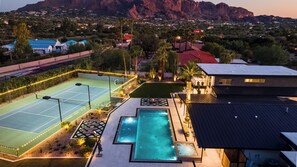 Ein Wohnhaus mit Tennisplatz, Schwimmbad und Blick auf eine gebirgige Landschaft.