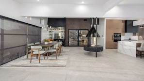 A modern kitchen with a central island, a dining area with a round table, and a large sliding door leading to a balcony. - Luxury 5BR Paradise Valley Estate - Pickleball, Tennis, Basketball Pool, and Spa (Paradise Valley)