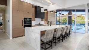 A modern kitchen with a large island, built-in appliances, and a view of a landscaped outdoor area. - Luxury 5BR Paradise Valley Estate - Pickleball, Tennis, Basketball Pool, and Spa (Paradise Valley)