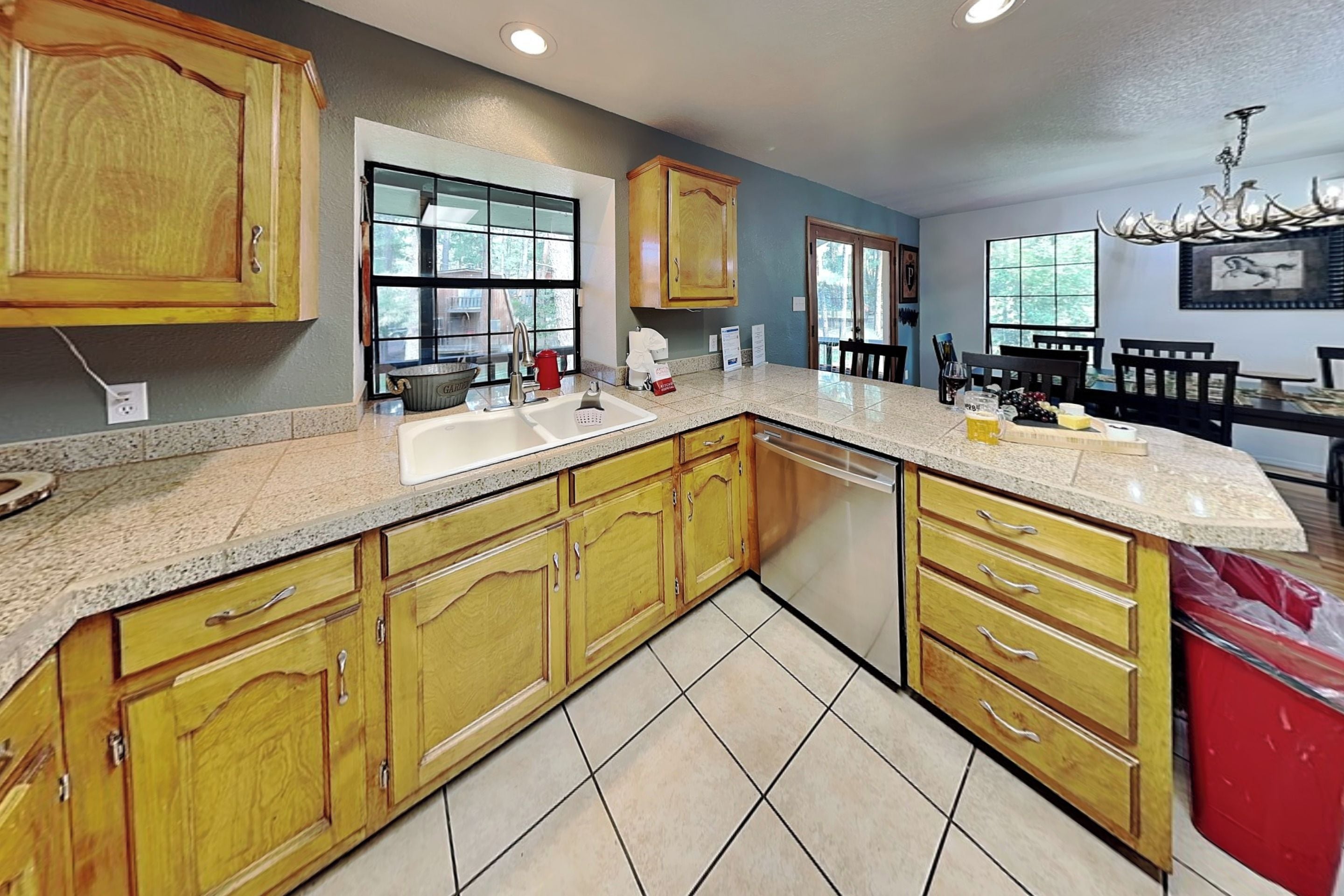 A kitchen with wooden cabinets, a granite countertop, a dishwasher, and a dining area with a chandelier.