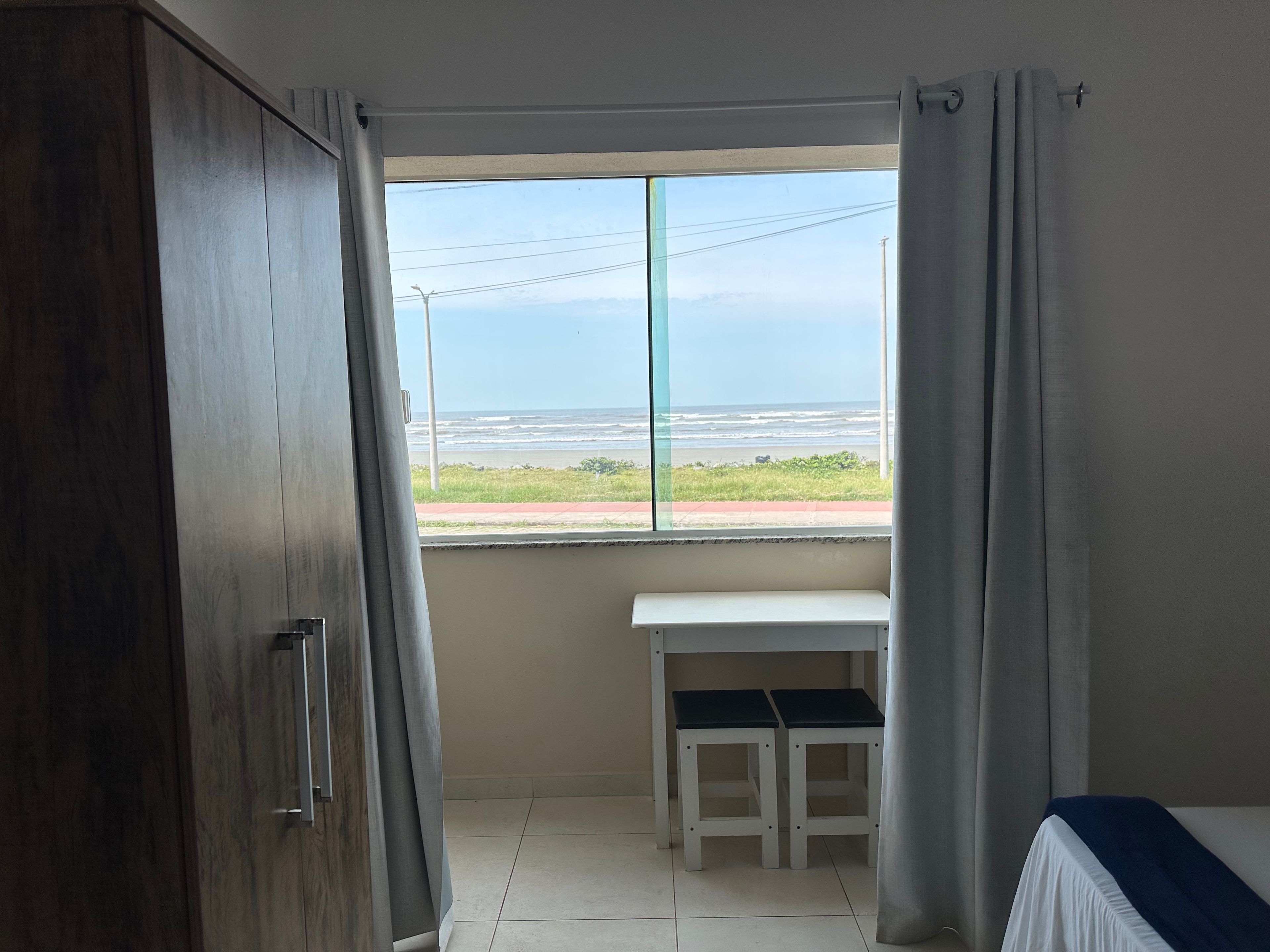 Ein Zimmer mit Blick auf den Strand, einem Schreibtisch und einem Bett.