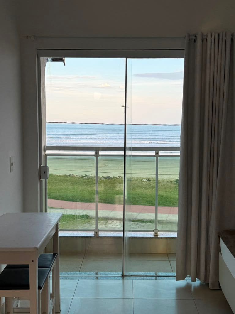 Una stanza con una porta scorrevole in vetro che dà su un balcone con vista sull'oceano.