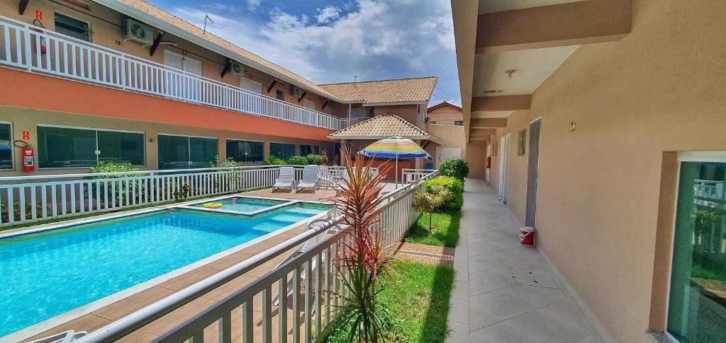 A hotel with a swimming pool, outdoor seating, and a covered area with a colorful umbrella.