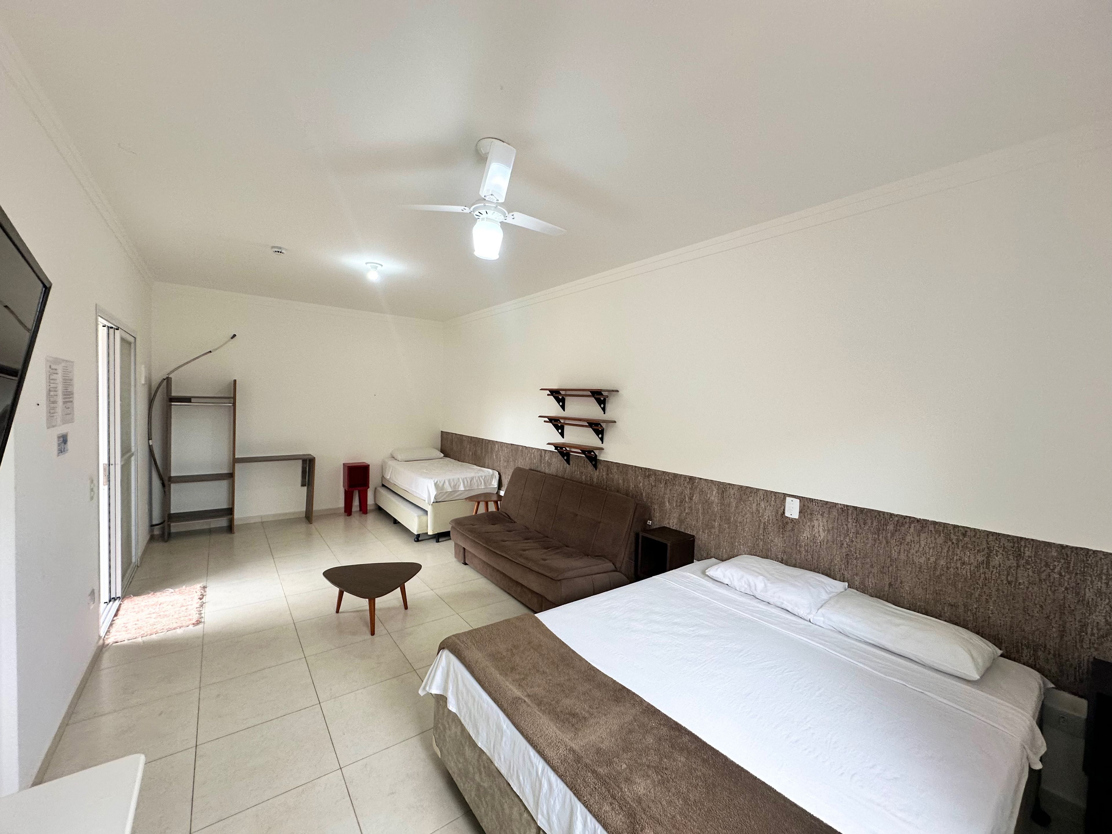 Une chambre à coucher comprenant un lit, un canapé, un bureau, une chaise, un ventilateur de plafond et une petite table.