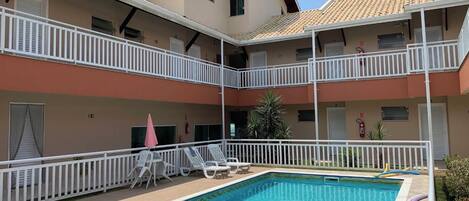 Un edificio de dos pisos con piscina, barandillas blancas y varios balcones.