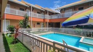 A multi-story building with a swimming pool, white railings, and a colorful umbrella.