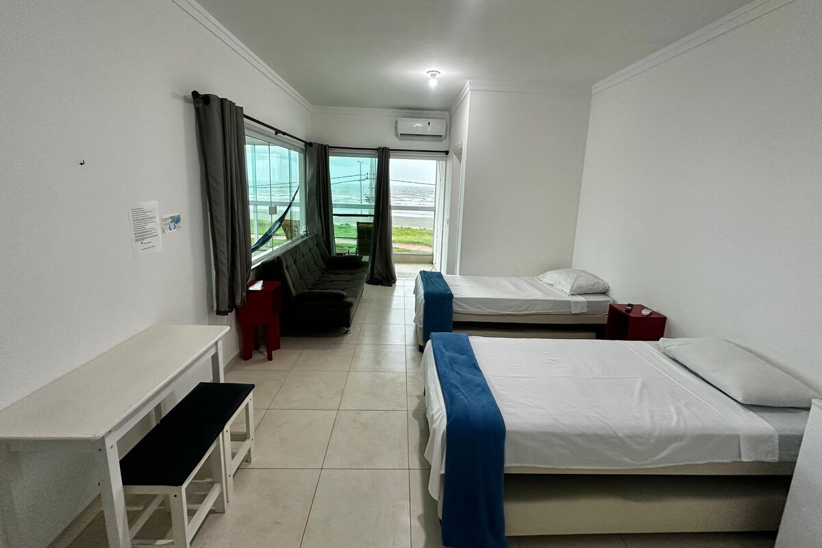 A hotel room with a bed, a desk, a chair, and a window with curtains.