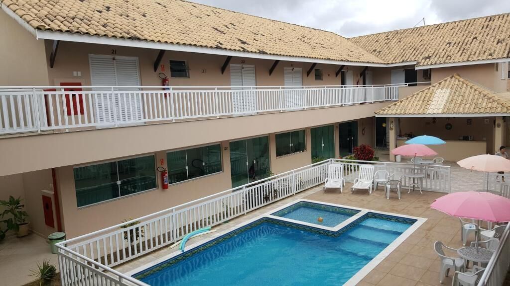 Ein Hotel mit Schwimmbad, Sitzgelegenheiten im Freien und einer überdachten Terrasse.