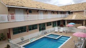 A hotel with a swimming pool, outdoor seating, and a covered patio area.