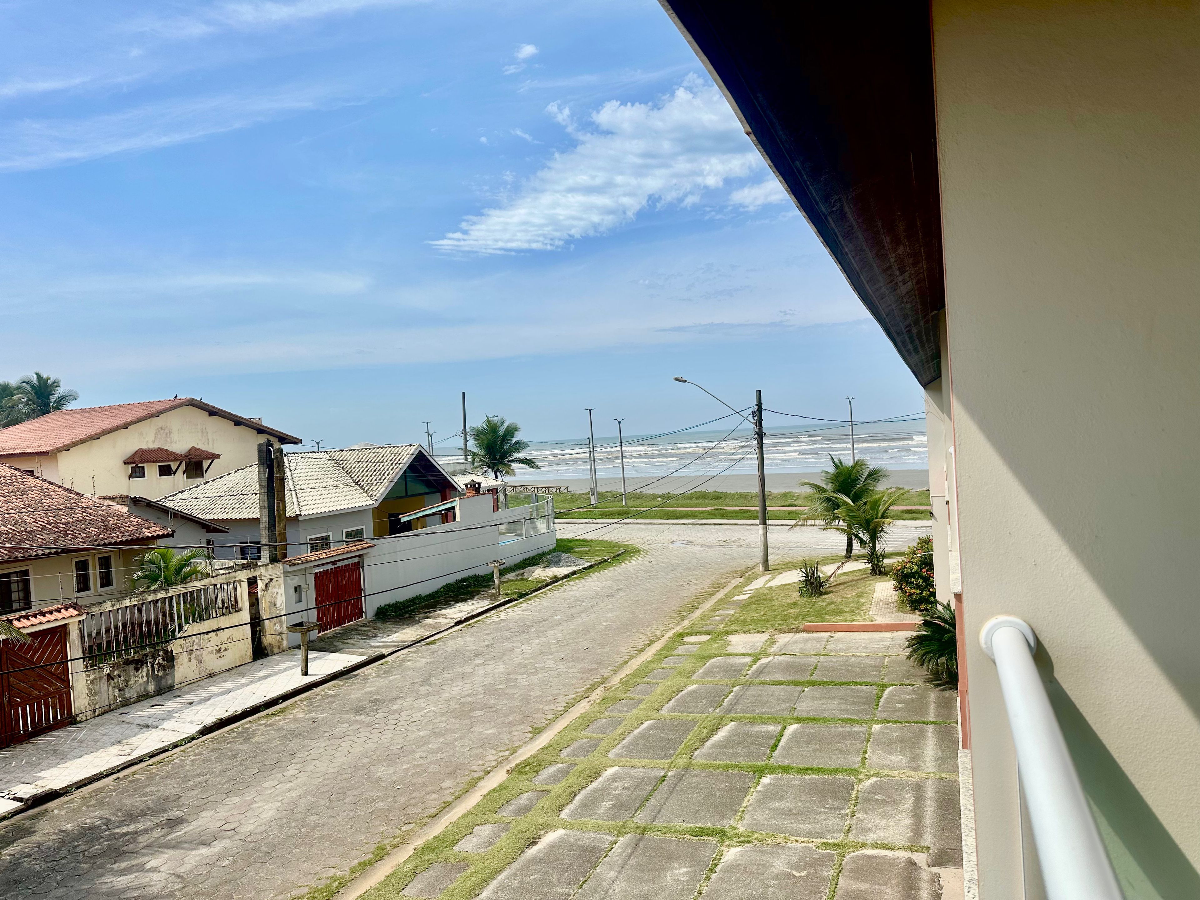 Una calle residencial con casas, una vía pavimentada y vista al océano.