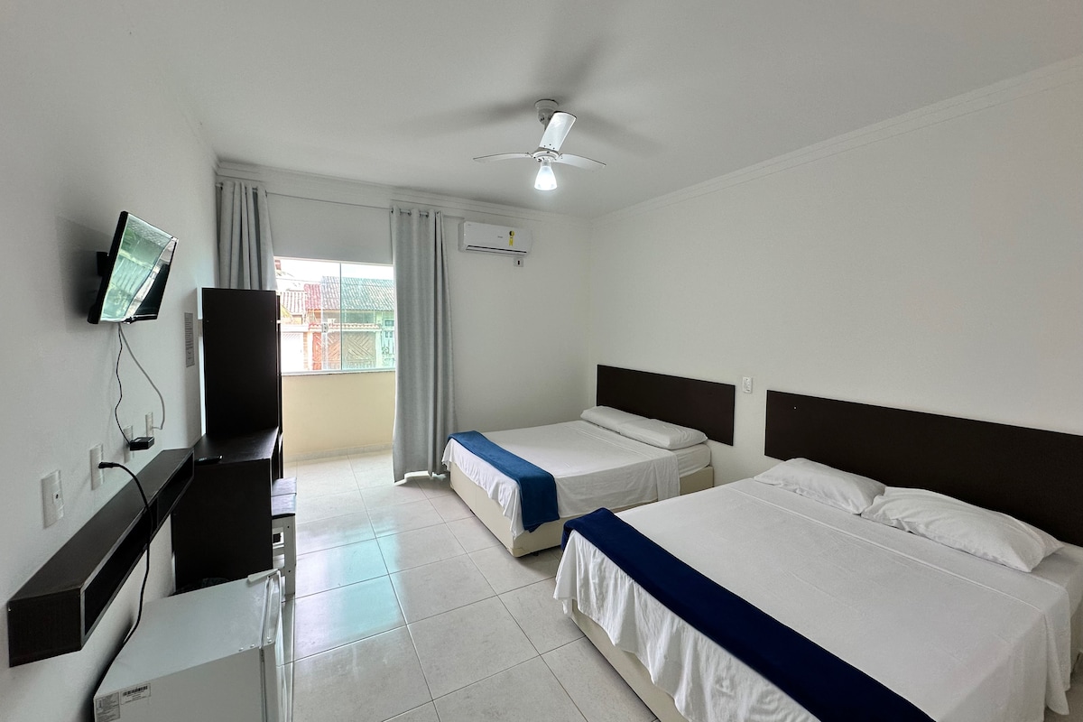 A hotel room with two beds, a TV, and a ceiling fan.