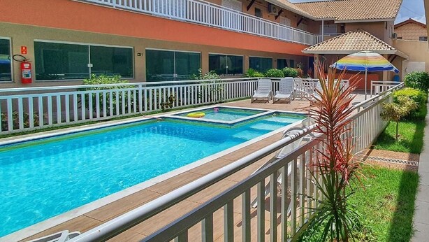 A hotel with a swimming pool, outdoor seating, and a balcony.