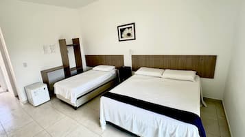 A hotel room with two single beds, a large bed, a ceiling fan, a small refrigerator, and a framed picture on the wall.