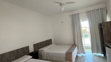 Habitación de hotel con dos camas, un ventilador de techo, una ventana con cortinas y un televisor.
