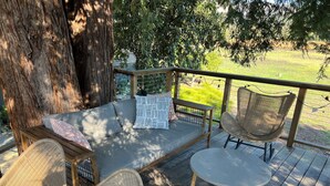 Une terrasse en bois avec un canapé, deux fauteuils en osier et une petite table.