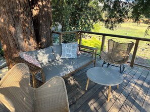 A wooden deck with a sofa, two wicker chairs, and a small table. - Charming 3-bedroom house in adorable Kenwood with cool vibes (Kenwood)