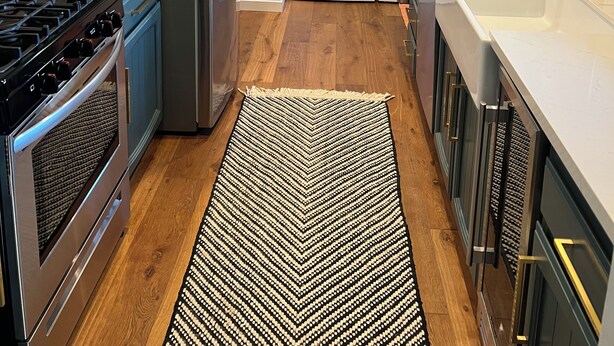 Une cuisine moderne dotée d’appareils électroménagers en acier inoxydable, de meubles de couleur sombre et d’un tapis à motifs.