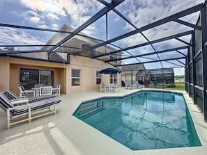 Ein Swimmingpool mit Liegestühlen und Sonnenschirmen, umgeben von einer überdachten Terrasse.
