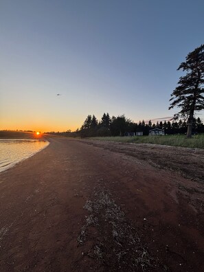 A dirt path leading to a cabin with a view of the sunset over a body of water. - Fogwell Oceanfront Retreat (Richmond)