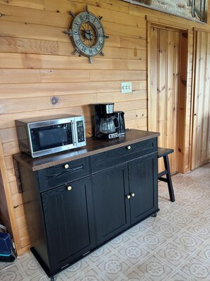 A wooden wall with a clock and a microwave on a cabinet. - Fogwell Oceanfront Retreat (Richmond)