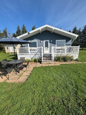 A single-story house with a covered porch, a small deck, and a patio area with outdoor furniture. - Fogwell Oceanfront Retreat (Richmond)