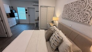 A bedroom with a bed, pillows, a nightstand, a lamp, and a wall art piece.