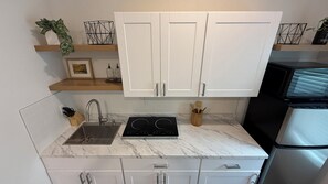 A compact kitchen with white cabinets, a built-in stove, and a stainless steel refrigerator.
