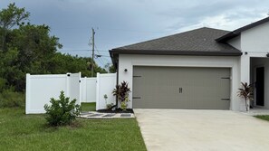 A modern two-story house with a garage, a white picket fence, and a well-maintained lawn.