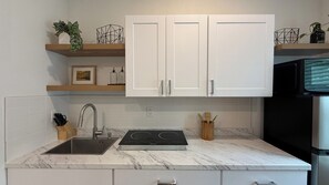 A modern kitchen with white cabinets, a stainless steel sink, and a built-in stovetop.