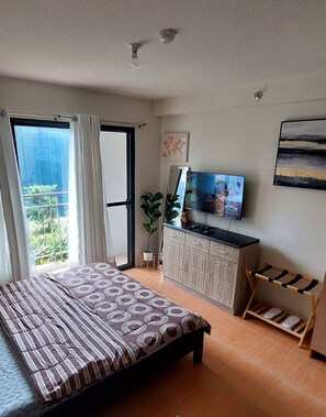 Quarto com cama, televisão, armário e varanda.