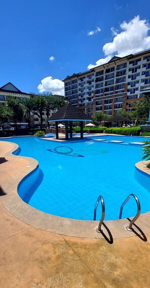 Piscina com um gazebo, cercada por um edifício com varandas.