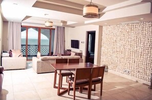 Una sala de estar moderna con comedor, un ventanal con cortinas y una pared de piedra.