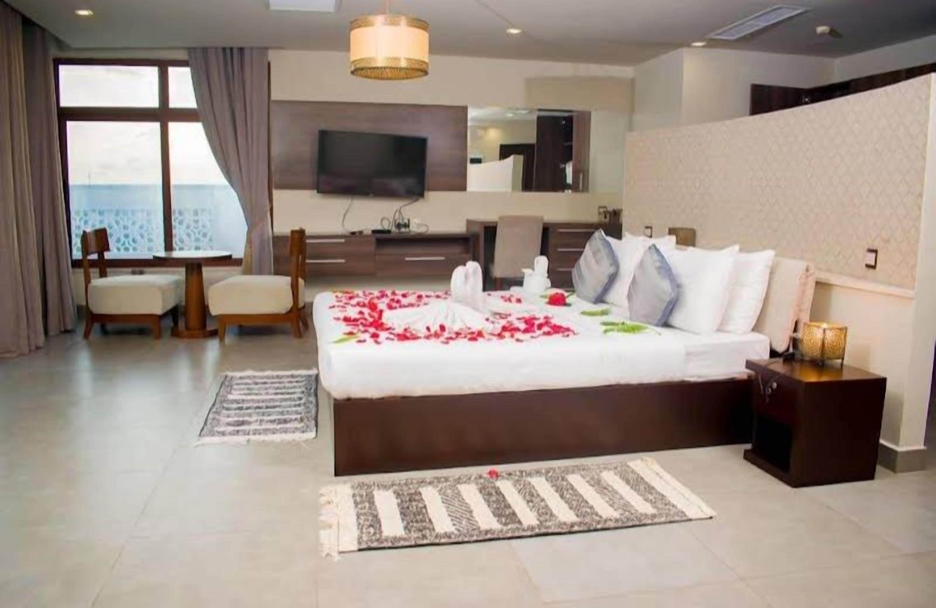 Habitación de hotel con una cama grande, televisión, escritorio y vista al mar.