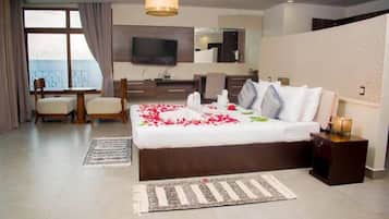Habitación de hotel con una cama grande, televisión, escritorio y vista al mar.