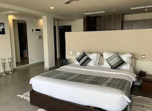 Un dormitorio de hotel moderno con una cama grande, cabecera, mesitas de noche y un espejo.