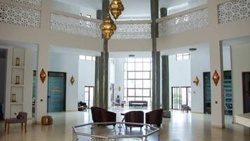 Un hall d’entrée spacieux avec un plafond haut, un espace salon central et une grande fenêtre laissant entrer la lumière naturelle.