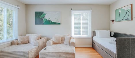 Quarto moderno com sofá-cama, espreguiçadeira e uma cama de solteiro.