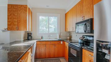 A kitchen with wooden cabinets, a stainless steel refrigerator, a microwave, and a stove.
