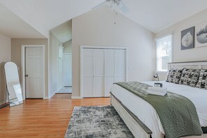 Ein Schlafzimmer mit einem Bett, einem Deckenventilator, einem Kleiderschrank und einer Tür.