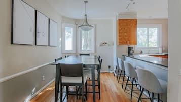 A modern kitchen with a dining area, wooden flooring, and a pendant light.