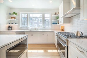 A modern kitchen with white cabinetry, a built-in oven, a gas stove, and a window with a view of buildings. - Seascape North View Townhome, Fireplace & Pet friendly (Depoe Bay)