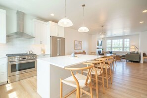 Eine moderne Küche mit Kochinsel, Edelstahlgeräten und Holzstühlen.