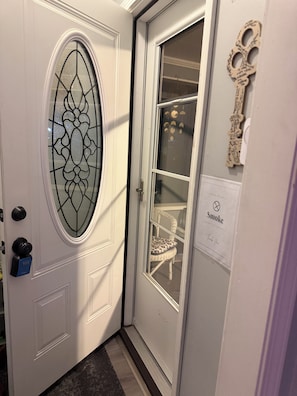 Une porte blanche avec un panneau en verre, un porte-clés et un panneau indiquant « Il est interdit de fumer à l’intérieur ».